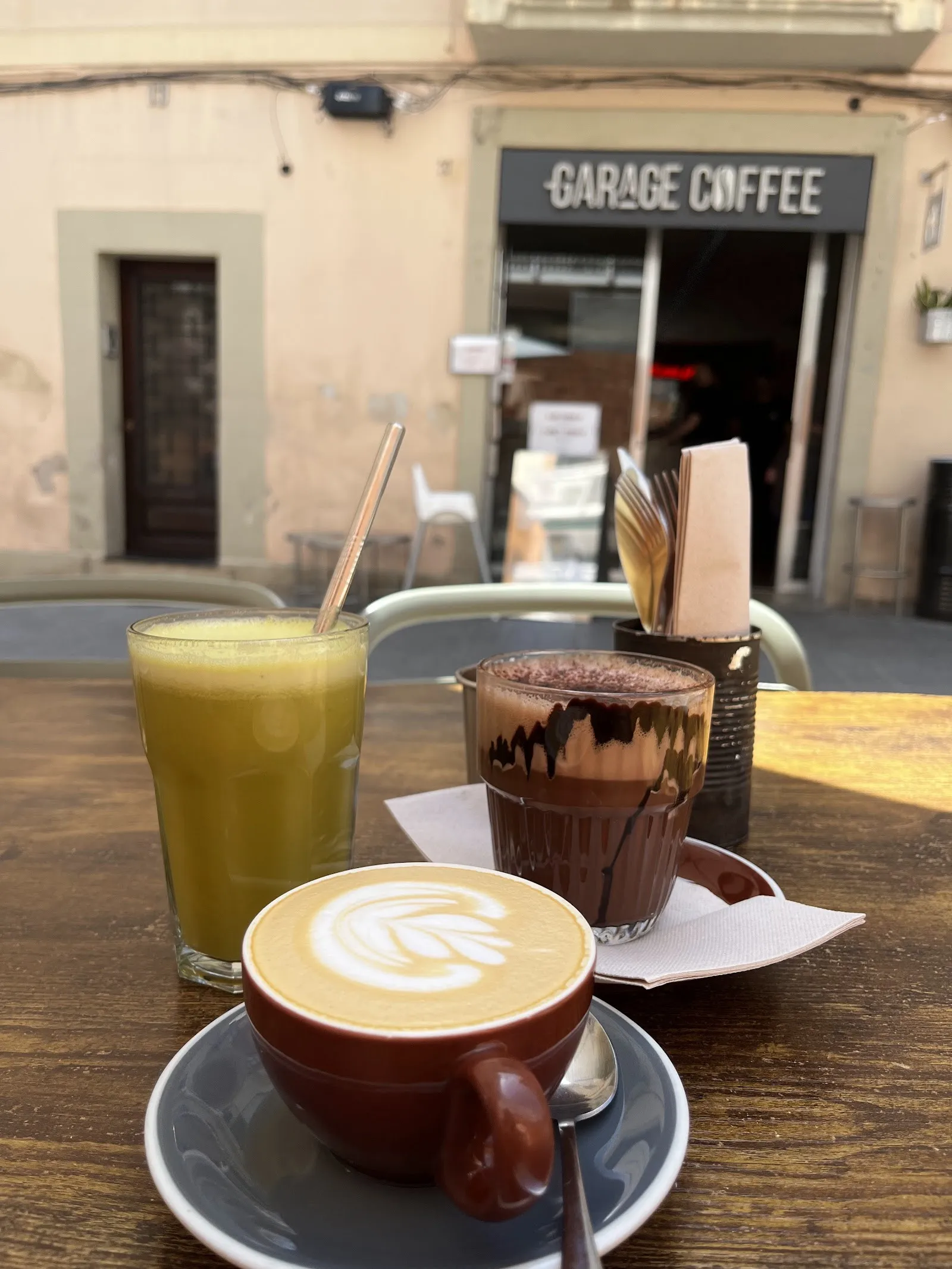 Un café, un zumo y un chocolate en la terraza, con la entrada del Garage detrás