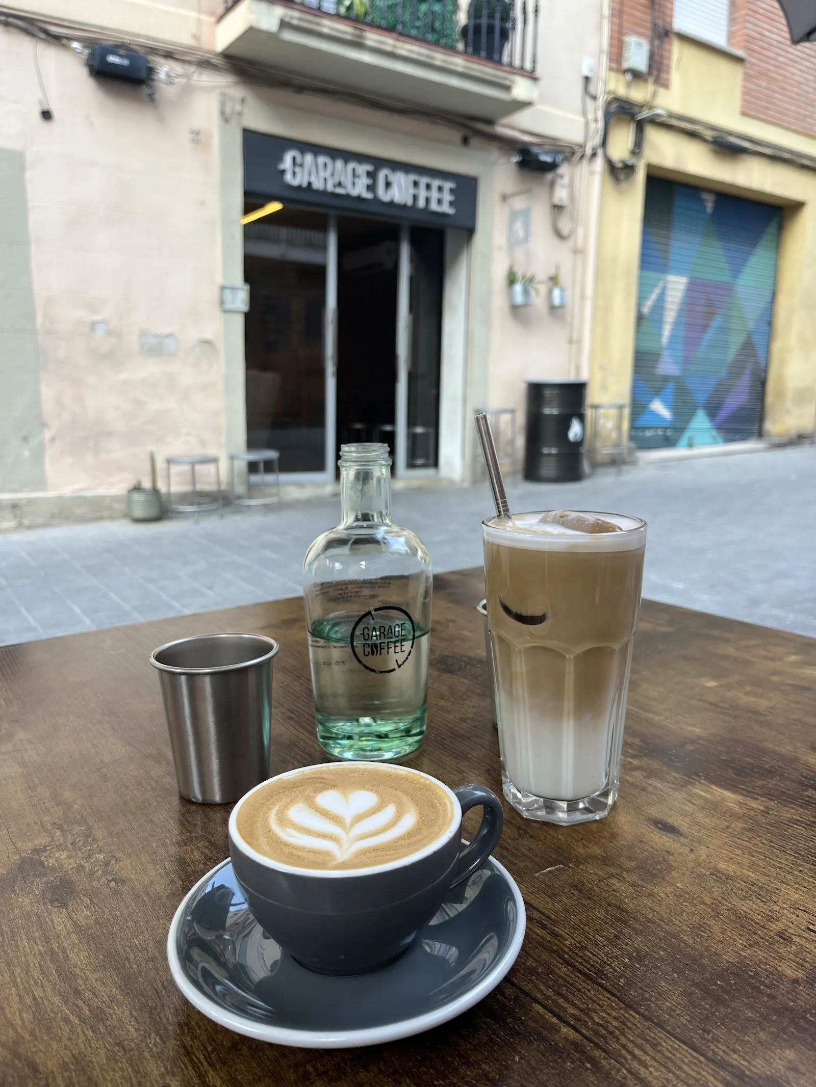 Un café con arte latte y un café con hielo en la terraza, frente a la fachada